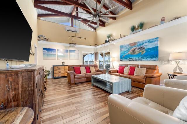 living area featuring high vaulted ceiling, a ceiling fan, beam ceiling, and wood finished floors