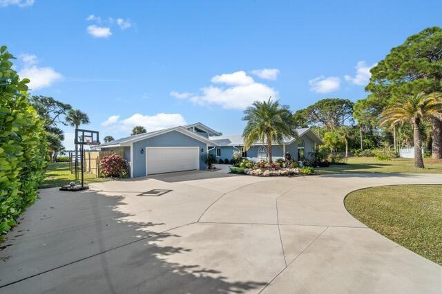 ranch-style house featuring concrete driveway, a front lawn, and an attached garage