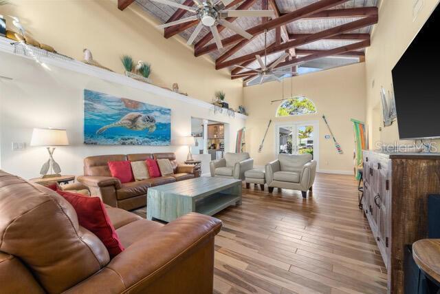 living room featuring a ceiling fan, beam ceiling, high vaulted ceiling, and wood finished floors