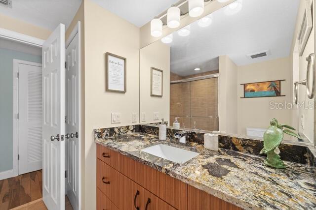 full bathroom featuring visible vents, a stall shower, vanity, wood finished floors, and baseboards