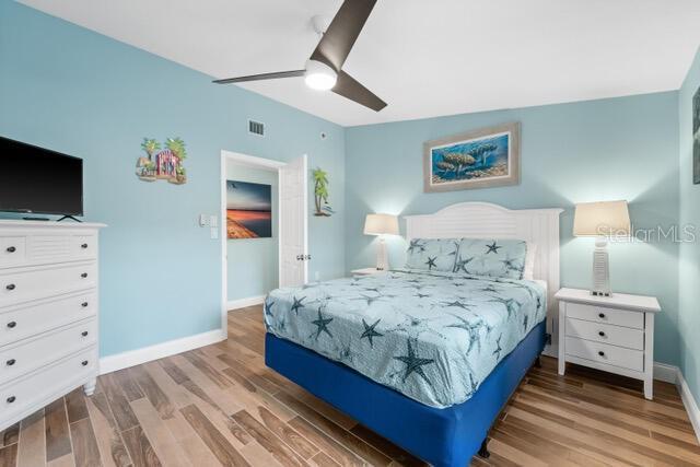 bedroom featuring a ceiling fan, wood finished floors, visible vents, and baseboards