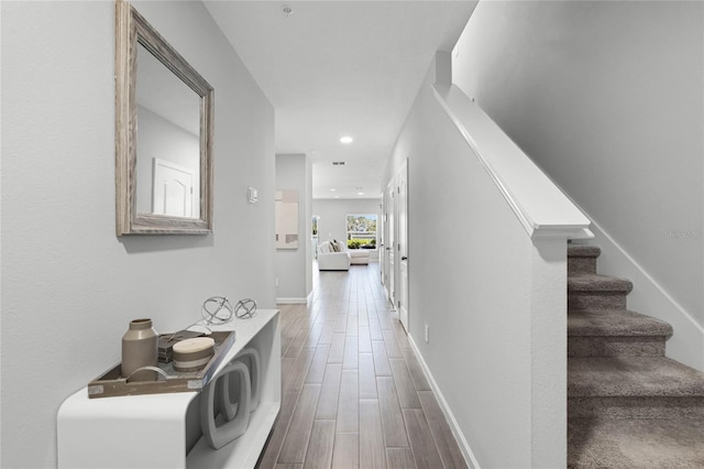 hallway with wood finish floors, stairway, baseboards, and recessed lighting