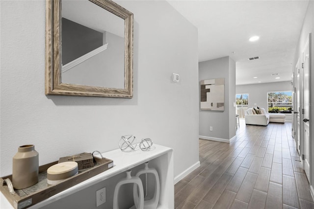 hall featuring baseboards, visible vents, wood finished floors, and recessed lighting