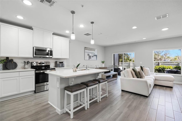 kitchen featuring visible vents, stainless steel appliances, and open floor plan