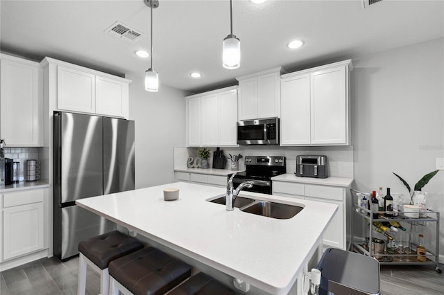 kitchen featuring stainless steel appliances, tasteful backsplash, visible vents, wood finished floors, and a kitchen bar