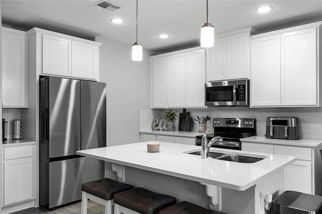 kitchen with appliances with stainless steel finishes, a sink, visible vents, and tasteful backsplash