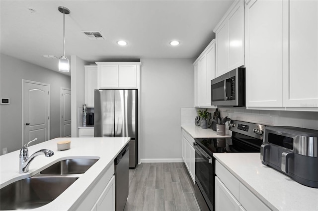 kitchen featuring stainless steel appliances, a sink, visible vents, white cabinetry, and tasteful backsplash