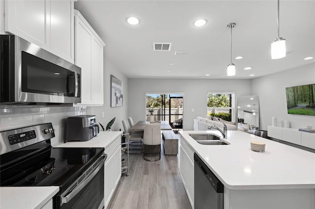 kitchen with stainless steel appliances, light countertops, visible vents, open floor plan, and a sink