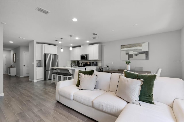 living room with baseboards, visible vents, wood finished floors, and recessed lighting