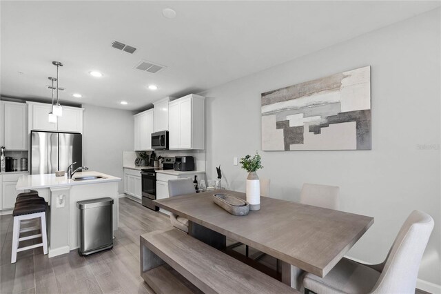 dining space with light wood-type flooring, visible vents, and recessed lighting