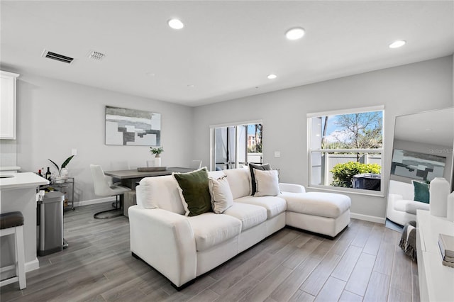 living room featuring light wood finished floors, baseboards, visible vents, and recessed lighting