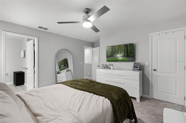 bedroom with light carpet, baseboards, visible vents, ceiling fan, and ensuite bathroom