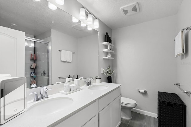 bathroom featuring toilet, a stall shower, a sink, and visible vents