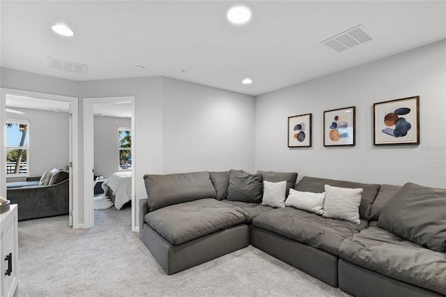 living room with recessed lighting, visible vents, and light colored carpet