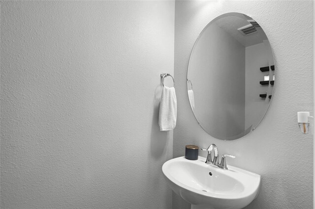 bathroom with a textured wall and a sink