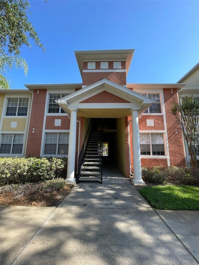 view of property with driveway, a carport, and stairs