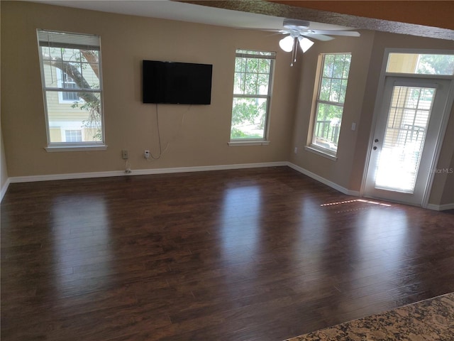 unfurnished living room featuring dark wood-style flooring, ceiling fan, and baseboards