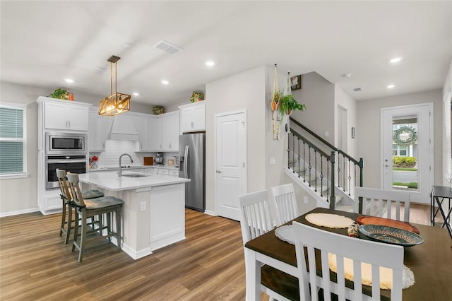 kitchen featuring stainless steel appliances, white cabinets, light countertops, and wood finished floors