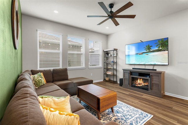 living room with a glass covered fireplace, recessed lighting, wood finished floors, and baseboards