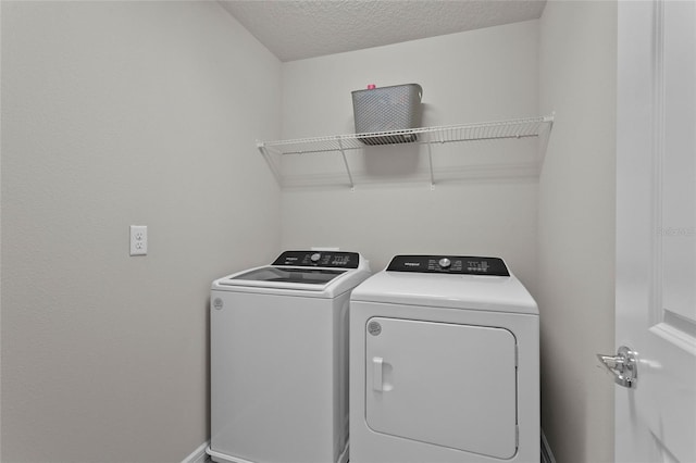 laundry area with a textured ceiling, laundry area, separate washer and dryer, and baseboards