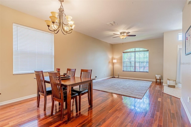 dining room featuring visible vents, ceiling fan with notable chandelier, hardwood / wood-style flooring, and baseboards