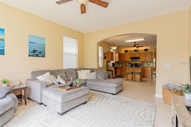 living room with arched walkways, ceiling fan, and light tile patterned floors