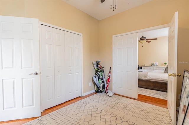 bedroom featuring ceiling fan, a closet, wood finished floors, and baseboards