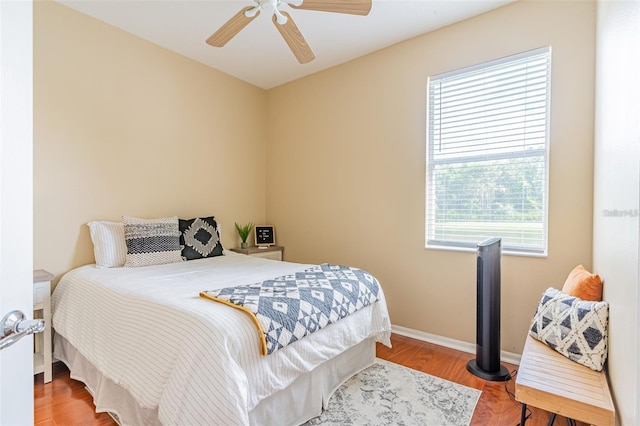 bedroom featuring ceiling fan, baseboards, and wood finished floors