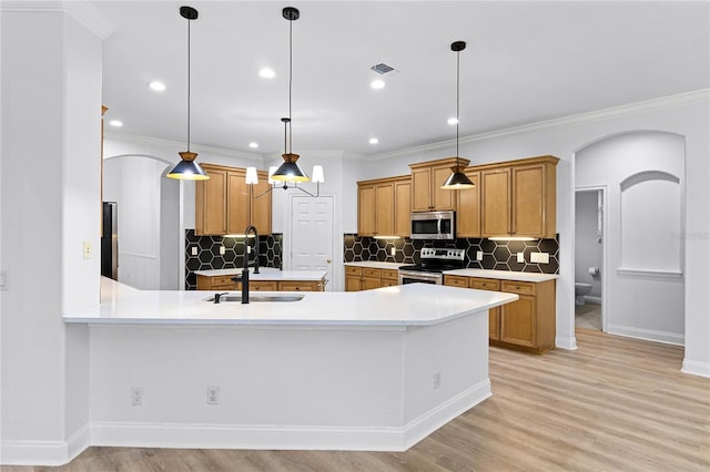 kitchen featuring arched walkways, visible vents, light wood-style flooring, appliances with stainless steel finishes, and a sink