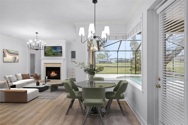 dining space with plenty of natural light, a chandelier, crown molding, and wood finished floors