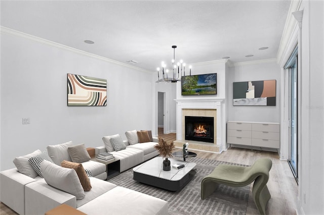 living room with a fireplace, visible vents, an inviting chandelier, light wood-style floors, and ornamental molding