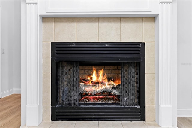 interior details featuring a tiled fireplace, wood finished floors, and baseboards