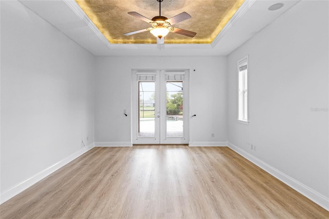 spare room with a tray ceiling, french doors, and baseboards