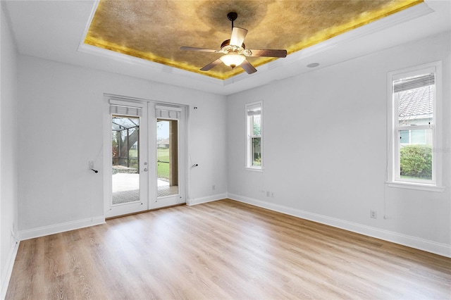 spare room featuring a raised ceiling, baseboards, french doors, and wood finished floors