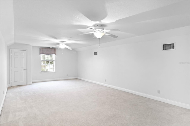 empty room with baseboards, visible vents, a ceiling fan, and light colored carpet