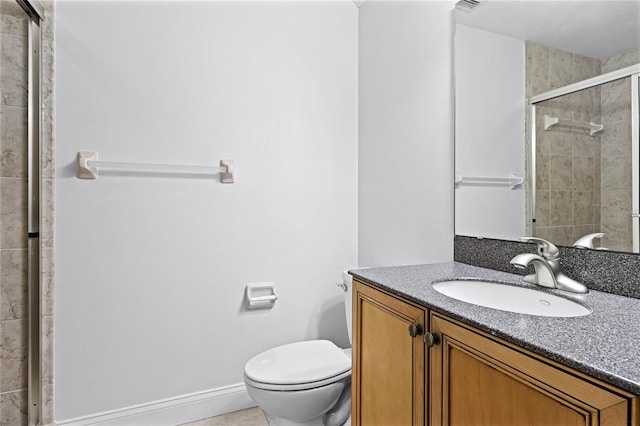 bathroom with baseboards, tiled shower, vanity, and toilet