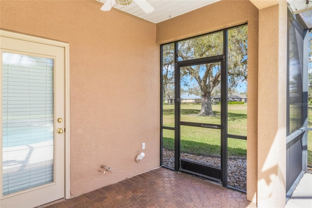 doorway with a textured wall and ceiling fan