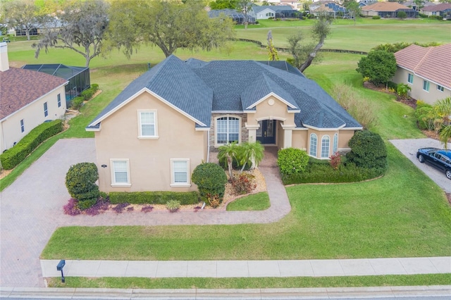 view of front of property with stucco siding, a shingled roof, a front yard, a residential view, and driveway