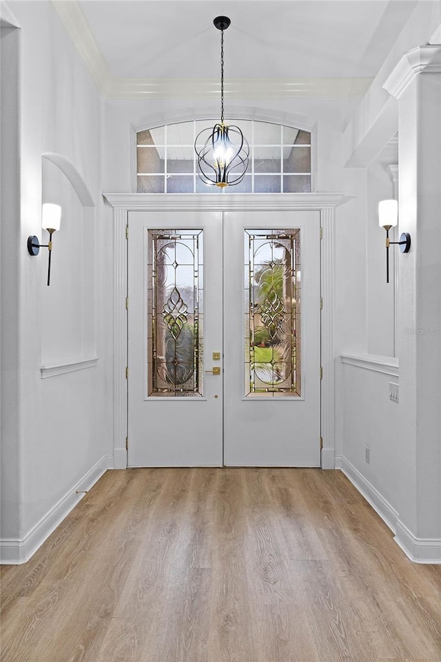 entrance foyer featuring french doors, crown molding, an inviting chandelier, wood finished floors, and baseboards