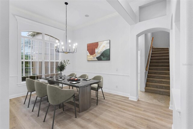 dining area featuring baseboards, arched walkways, stairs, light wood-style floors, and a notable chandelier