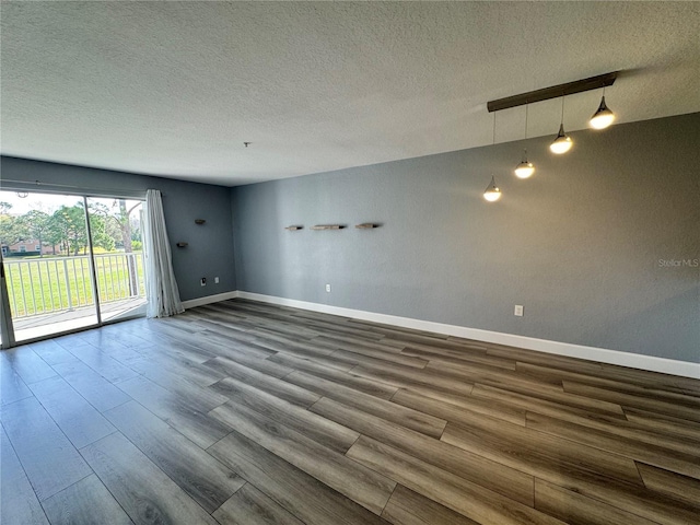 empty room with dark wood-style floors, a textured ceiling, and baseboards