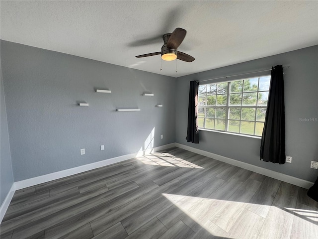 spare room featuring a textured ceiling, baseboards, and wood finished floors