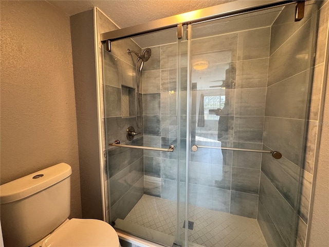 bathroom featuring a textured wall, a stall shower, and toilet