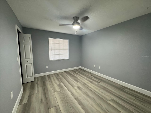 unfurnished bedroom featuring a textured ceiling, wood finished floors, a ceiling fan, and baseboards