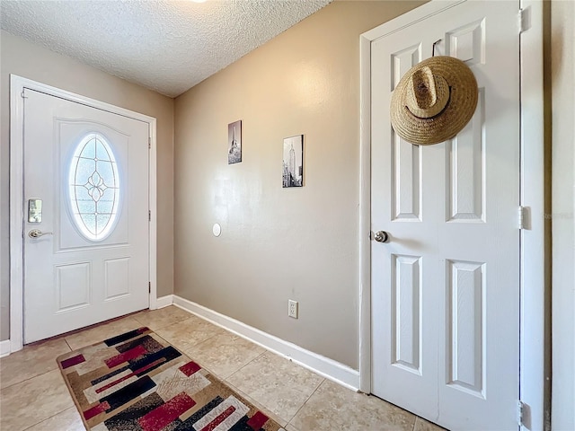 foyer with a textured ceiling, baseboards, and light tile patterned floors