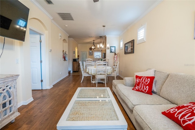 living area with visible vents, dark wood-type flooring, ornamental molding, arched walkways, and baseboards