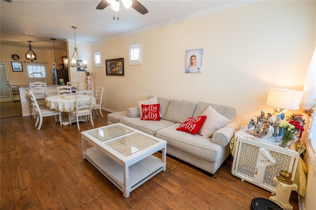 living area featuring ceiling fan with notable chandelier, crown molding, wood finished floors, and baseboards