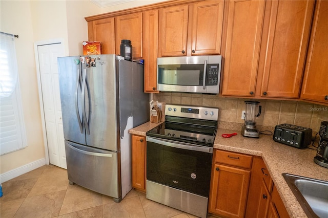 kitchen featuring brown cabinetry, decorative backsplash, and appliances with stainless steel finishes