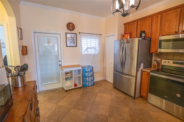 kitchen featuring brown cabinetry, an inviting chandelier, arched walkways, appliances with stainless steel finishes, and crown molding