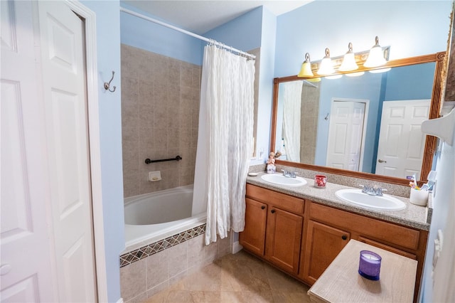 full bathroom with double vanity, tiled shower / bath, and a sink